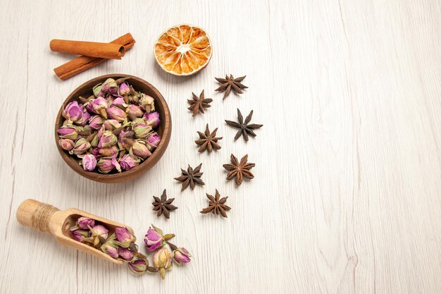 Vista dall'alto fiori viola con cannella su scrivania bianca sapore di fiori di colore secco