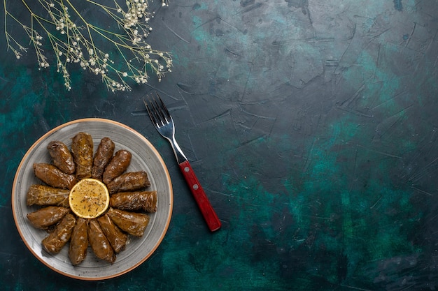 Vista dall'alto foglia dolma delizioso pasto di carne orientale arrotolato all'interno di foglie verdi sulla scrivania blu carne cibo cena piatto verdure salute