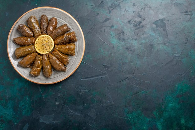 Vista dall'alto foglia dolma delizioso pasto di carne orientale arrotolato all'interno di foglie verdi sulla scrivania blu scuro pasto a base di carne cibo cena verdure salute calorie