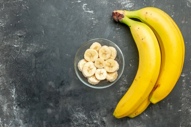 Vista dall'alto fonte di nutrizione fascio di banane fresche e tritato in un vaso di vetro su sfondo grigio