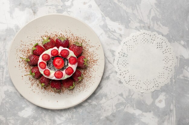 Vista dall'alto fragole rosse fresche con torta sulla scrivania bianca