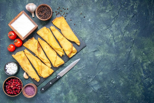 Vista dall'alto frittelle arrotolate foderate con pomodori su sfondo scuro torta di colore hotcake torta di pasta di carne torta di pasticceria dolce spazio libero