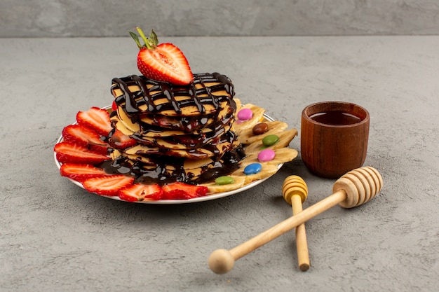 vista dall'alto frittelle dolci con frutta e cioccolato sul pavimento grigio