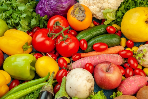 Vista dall'alto frutta e verdura melanzane peperoni mele carota coriandolo cavolfiore cachi ravanello pomodorini su sfondo blu