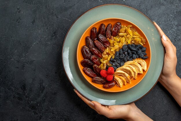 Vista dall'alto frutta secca con diverse uvetta e snack su uno spazio grigio