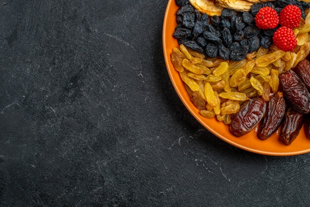 Vista dall'alto frutta secca con uvetta all'interno del piatto su uno spazio grigio scuro