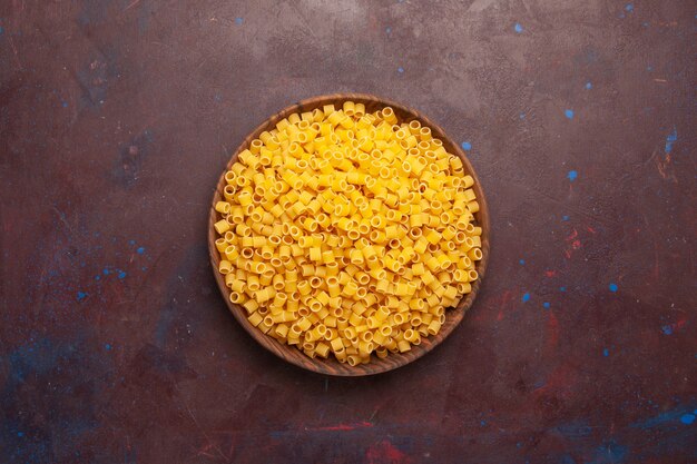 Vista dall'alto giallo pasta italiana cruda poco formata su sfondo scuro pasta cibo crudo impasto