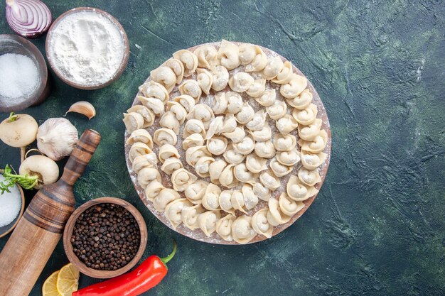 Vista dall'alto gnocchi crudi con farina e verdure su sfondo scuro pasta di carne piatto alimentare calorie colore verdure pasto