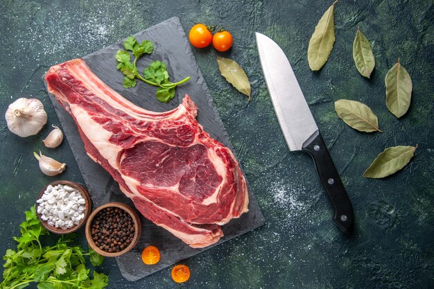 Vista dall'alto grande fetta di carne carne cruda con pepe e verdure su superficie scura