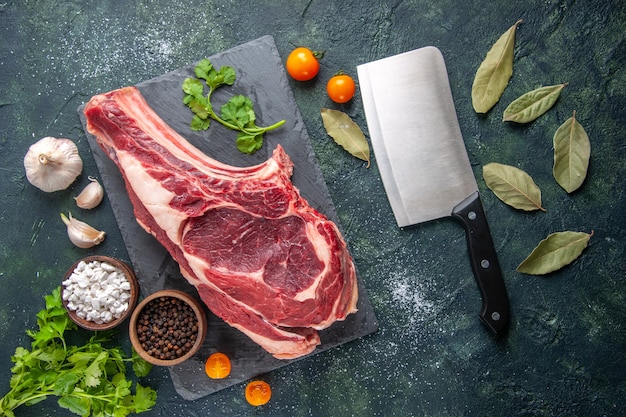 Vista dall'alto grande fetta di carne carne cruda con pepe e verdure su superficie scura