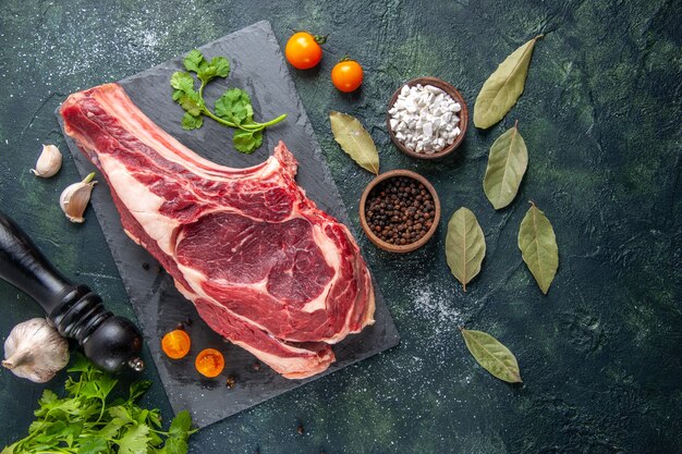 Vista dall'alto grande fetta di carne carne cruda con pepe e verdure su superficie scura