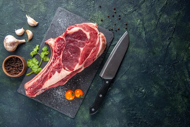 Vista dall'alto grande fetta di carne carne cruda con pepe su superficie scura