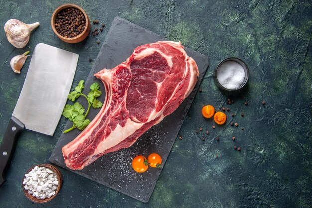 Vista dall'alto grande fetta di carne carne cruda con pepe su superficie scura