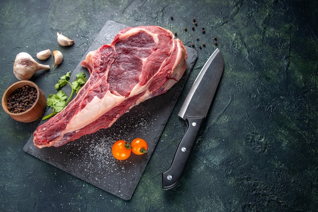 Vista dall'alto grande fetta di carne carne cruda con pepe su superficie scura