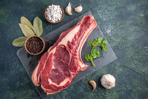 Vista dall'alto grande fetta di carne carne cruda con pepe su superficie scura