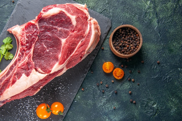 Vista dall'alto grande fetta di carne carne cruda con pepe su superficie scura