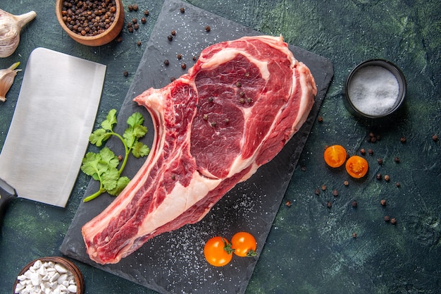 Vista dall'alto grande fetta di carne carne cruda con pepe su superficie scura