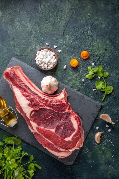 Vista dall'alto grande fetta di carne carne cruda con verdure su superficie scura