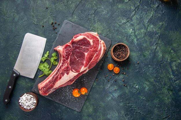 Vista dall'alto grande fetta di carne carne cruda con verdure su superficie scura