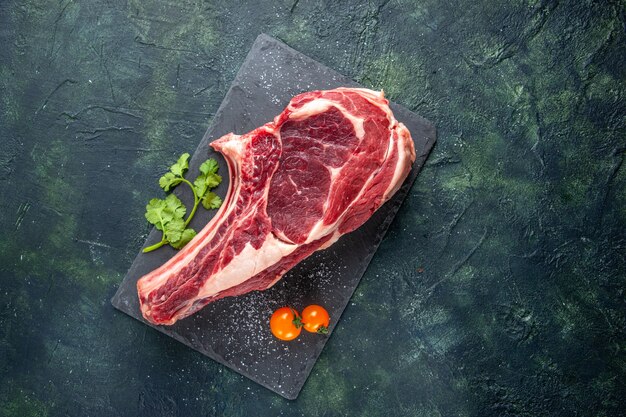 Vista dall'alto grande fetta di carne carne cruda su superficie blu scuro