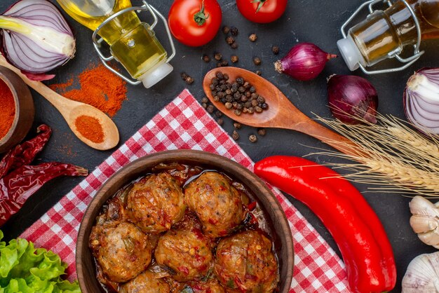 Vista dall'alto grande zuppa di polpette in una ciotola polvere di peperone rosso in una piccola ciotola lattuga cipolla bottiglia sul tavolo