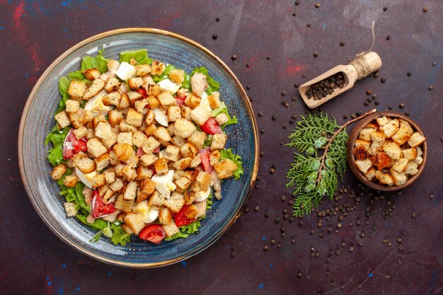 Vista dall'alto gustosa insalata caesar con piccole fette biscottate sulla scrivania scura