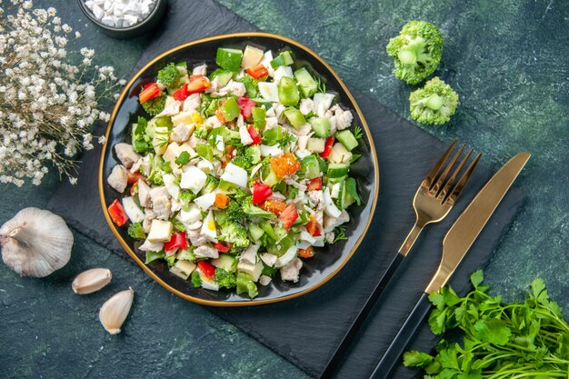 vista dall'alto gustosa insalata di verdure all'interno del piatto con forchetta su sfondo blu scuro ristorante pasto colore salute dieta fresca cucina pranzo cibo