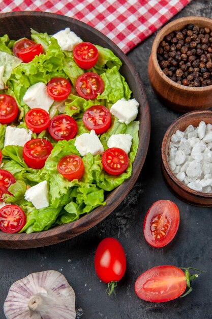 Vista dall'alto gustosa insalata di verdure con formaggio a fette pomodori e condimenti su sfondo scuro cibo pasto dieta pranzo salute colore