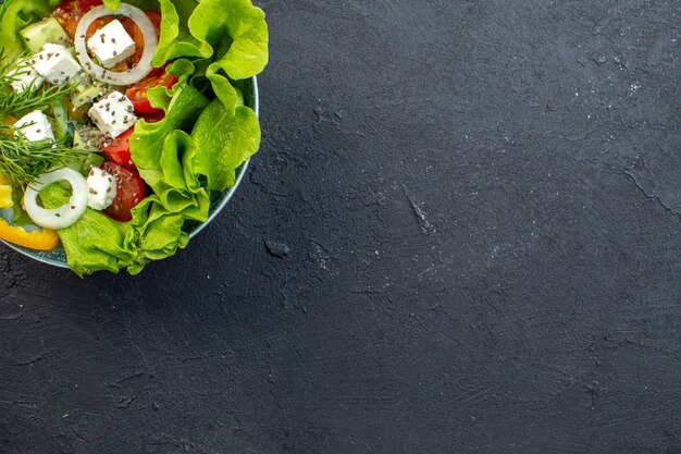 vista dall'alto gustosa insalata di verdure con formaggio cetrioli e pomodori su sfondo scuro