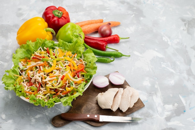 Vista dall'alto gustosa insalata di verdure con verdure a fette e intere verdure fresche e petto di pollo crudo su grigio, pasto di cibo insalata