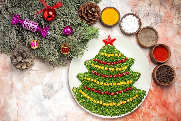 Vista dall'alto gustosa insalata verde a forma di albero di capodanno con condimenti su luce scrivania vacanza colore foto pasto salute natale