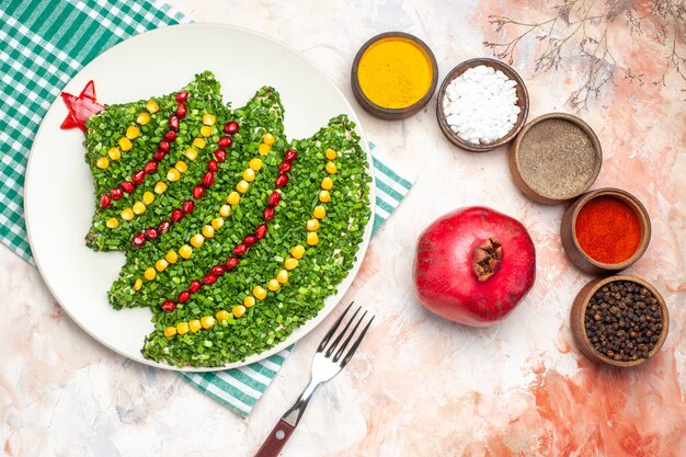 Vista dall'alto gustosa insalata verde a forma di albero di Capodanno con condimenti su sfondo chiaro