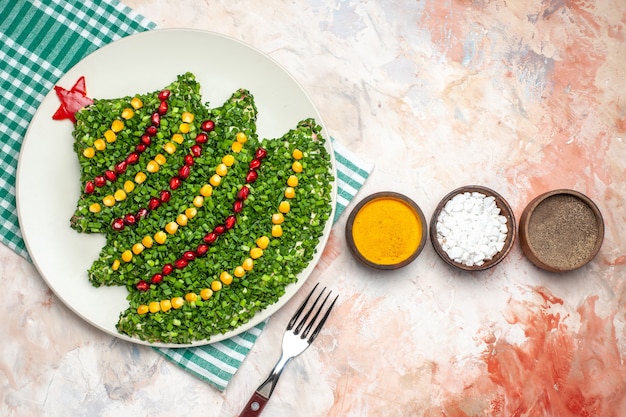 Vista dall'alto gustosa insalata verde a forma di albero di natale con condimenti su sfondo chiaro