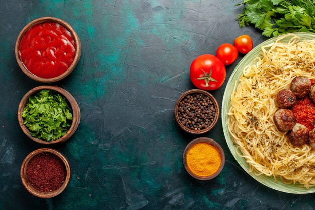 Vista dall'alto gustosa pasta italiana con polpette di carne e condimenti diversi sulla scrivania blu scuro