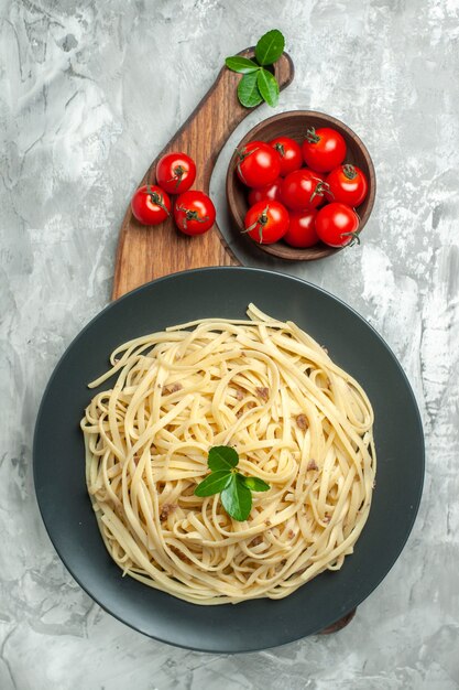 Vista dall'alto gustosa pasta italiana con pomodorini su sfondo chiaro