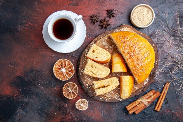 Vista dall'alto gustosa pasticceria dolce con una tazza di tè sulla superficie scura