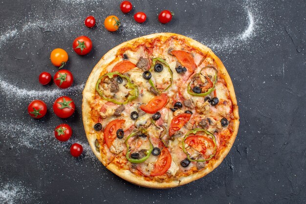 Vista dall'alto gustosa pizza al formaggio con pomodori rossi su superficie scura