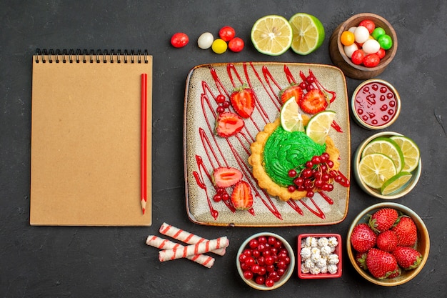 Vista dall'alto gustosa torta cremosa con frutta su sfondo scuro biscotto dolce colore dolce