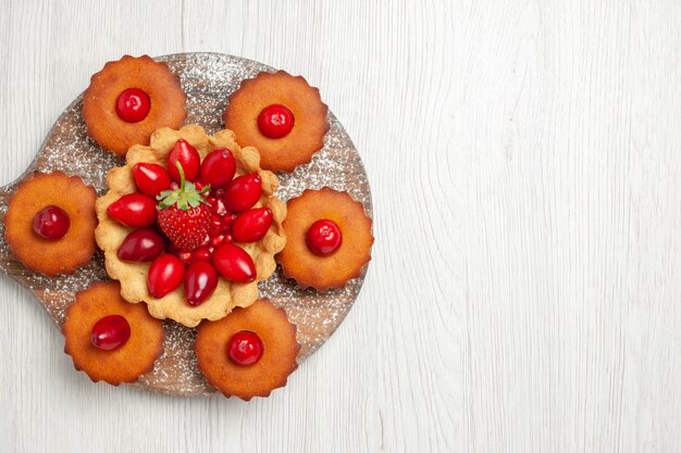 Vista dall'alto gustosa torta cremosa con torte e frutta sulla scrivania bianca