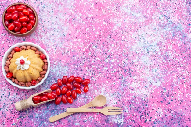 Vista dall'alto gustosa torta semplice con panna e arachidi fresche insieme a cornioli rossi freschi sulla luce intensa torta da scrivania biscotto bacca di noci dolci