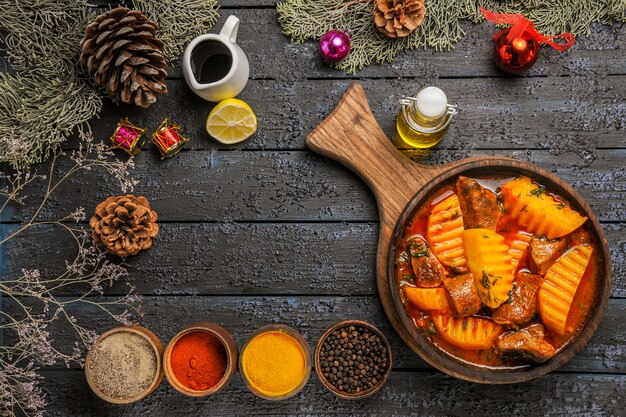 Vista dall'alto gustosa zuppa di carne con condimenti sulla scrivania scura