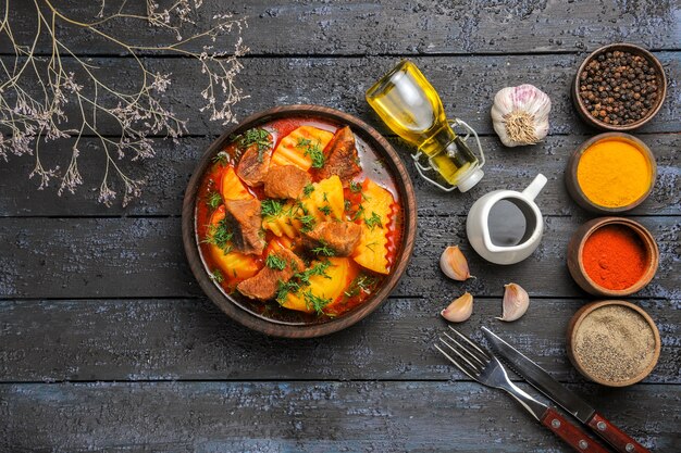 Vista dall'alto gustosa zuppa di carne con patate e verdure sulla scrivania scura