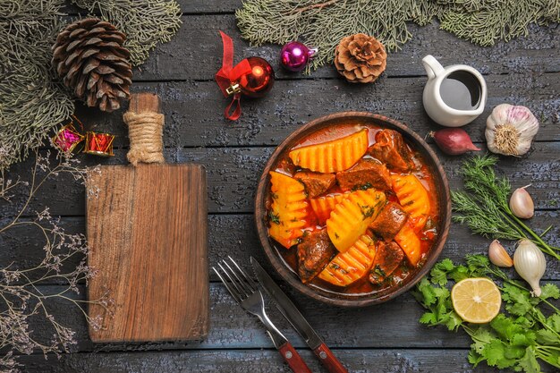 Vista dall'alto gustosa zuppa di carne con verdure e patate su una scrivania buia