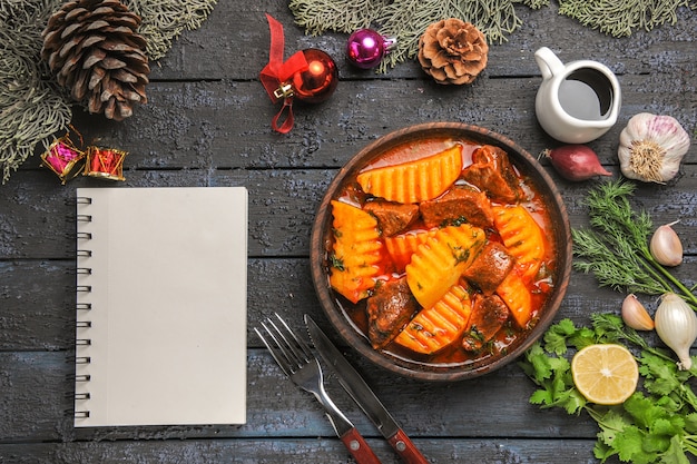 Vista dall'alto gustosa zuppa di carne con verdure e patate su una scrivania buia