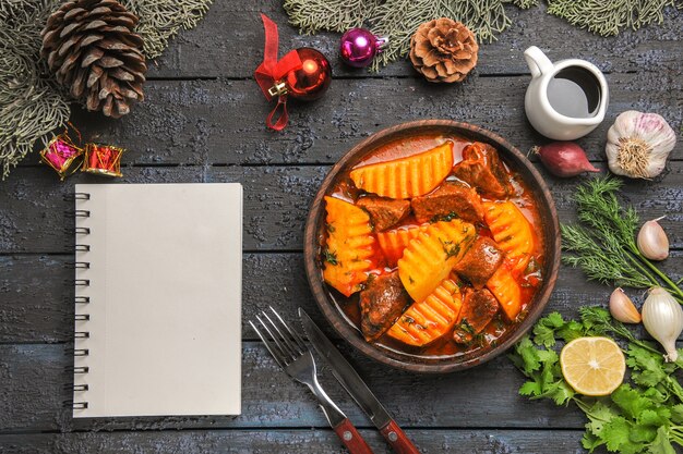 Vista dall'alto gustosa zuppa di carne con verdure e patate su una scrivania buia