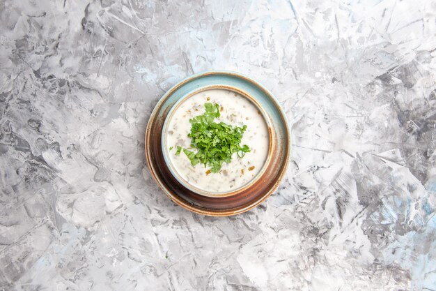 Vista dall'alto gustosa zuppa di yogurt dovga con verdure all'interno del piatto sul pasto di minestra di latte tavolo bianco