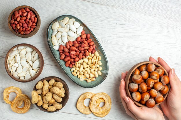 Vista dall'alto gustose arachidi fresche con semi bianchi e nocciole sul tavolo bianco