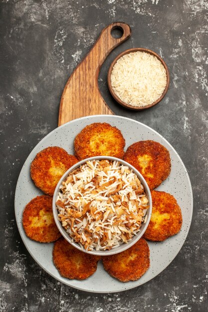 Vista dall'alto gustose cotolette fritte con riso cotto su polpetta di carne superficie grigio scuro