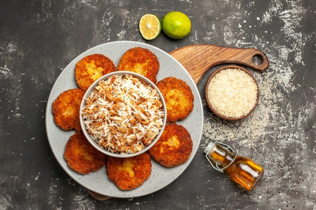 Vista dall'alto gustose cotolette fritte con riso cotto sul piatto di polpetta di carne superficie scura