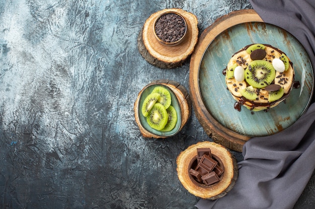 Vista dall'alto gustose frittelle con frutta a fette e cioccolato sulla superficie grigio scuro colore dolce colazione zucchero torta alla frutta dessert